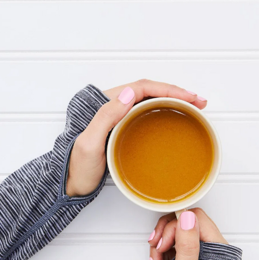 Hands holding a warm cup of bone broth rich in calcium